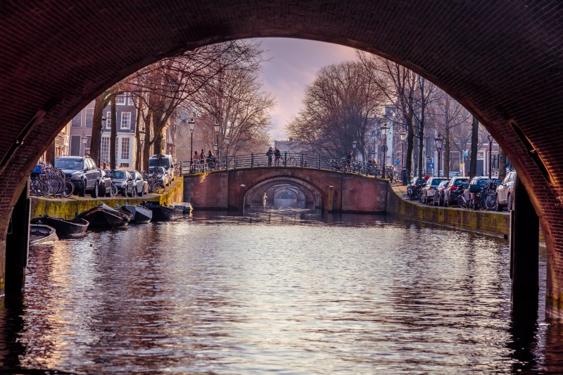 Samochody zaparkowane wzdłuż kanału w Amsterdamie. 